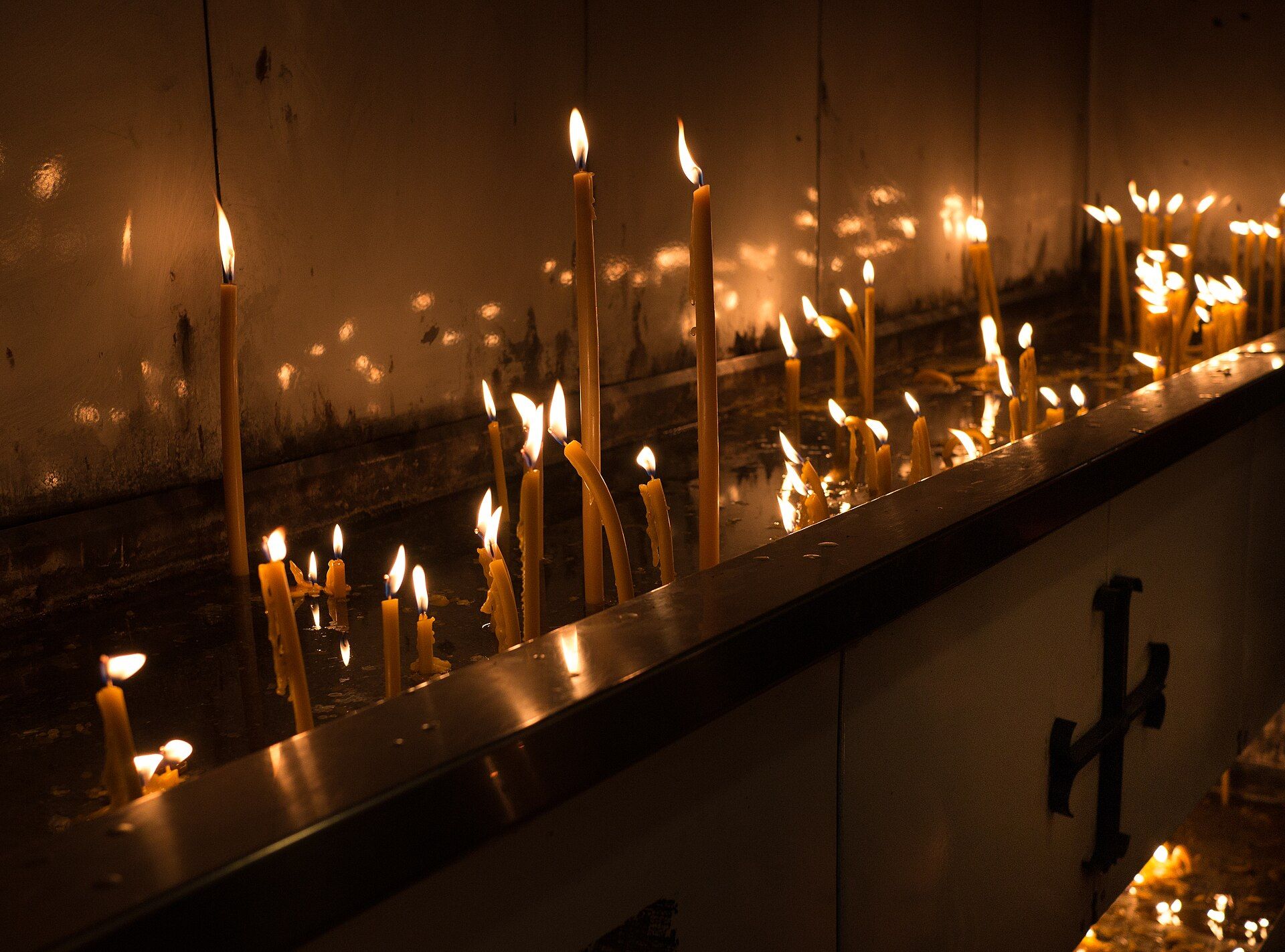 Rows of candles glowing in a quiet Orthodox church candle room